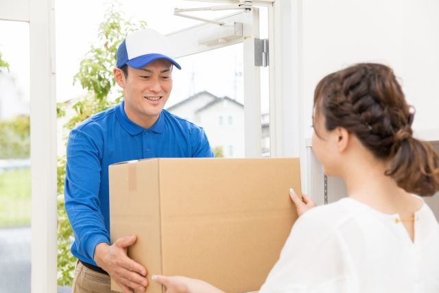 荷物を女性に渡す配送ドライバー