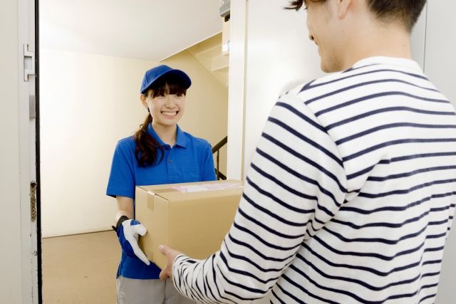 ダンボールに入った荷物を届ける配達ドライバー