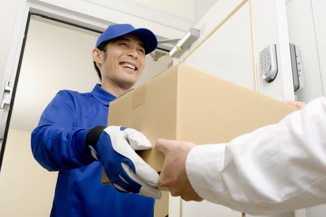 玄関で荷物を渡す配送スタッフの男性