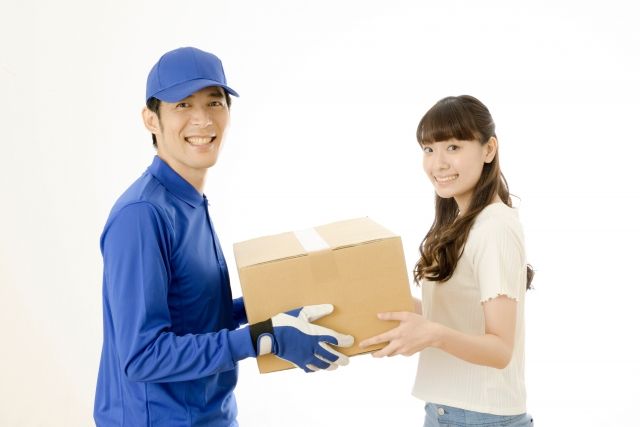 荷物を配送スタッフから受け取る女性